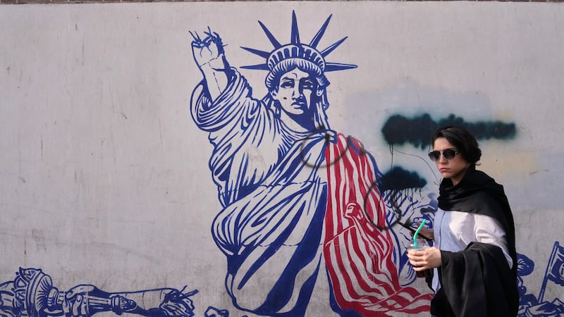 A woman walks past an anti-American mural on the wall of the former U.S. Embassy, now a...